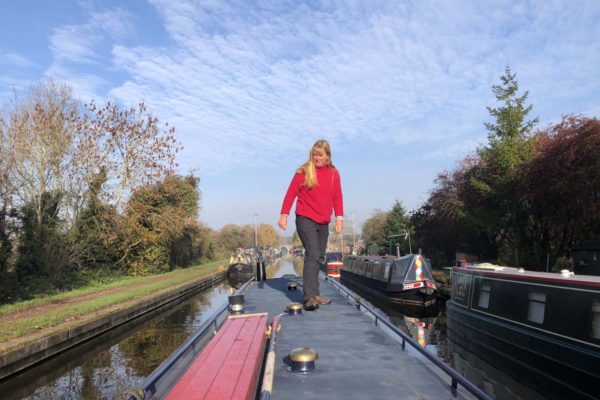 a women standing on top of a narrow boat